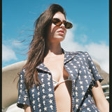 Female model looking down at camera wearing shirt unbuttoned over a bikini top
