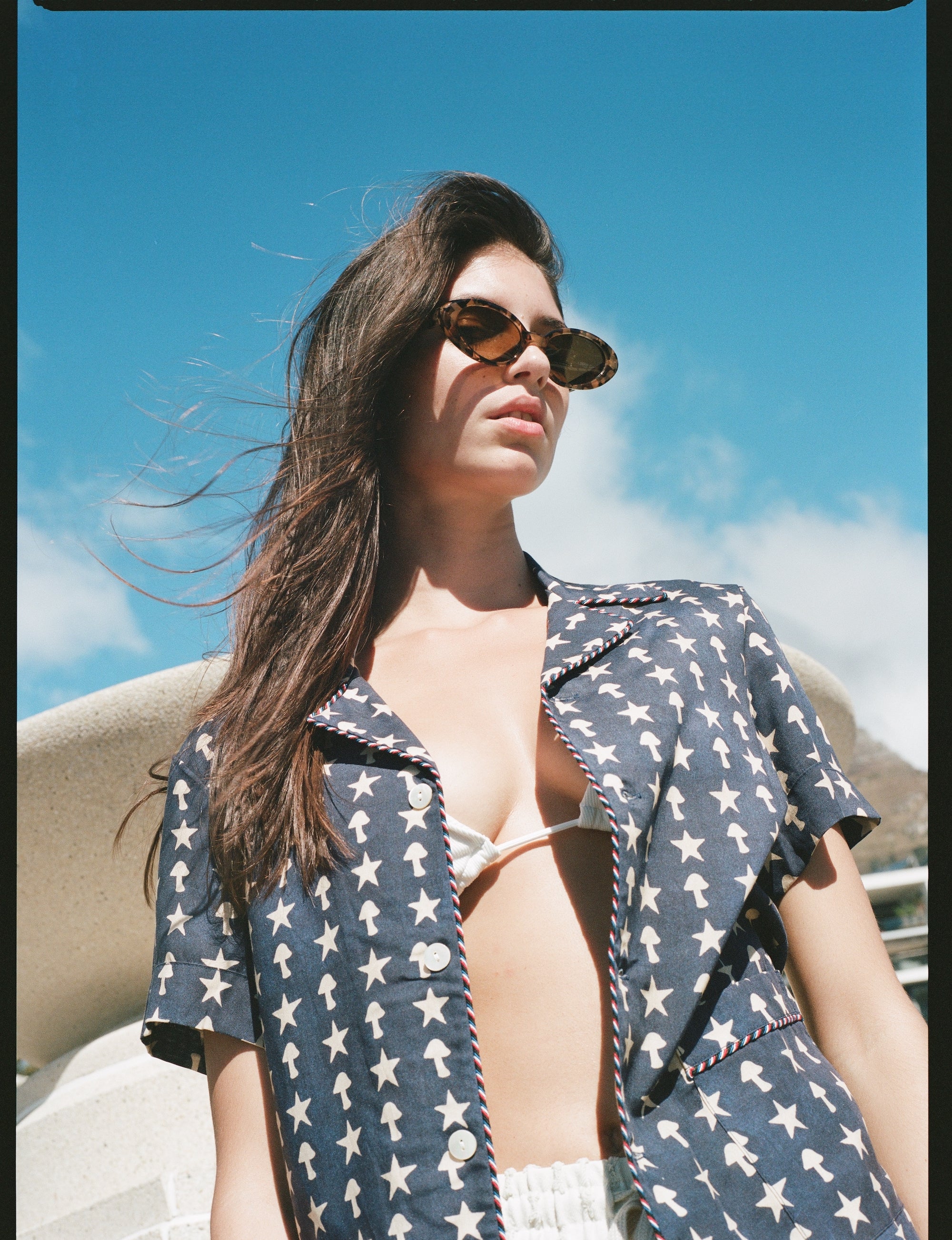 Female model looking down at camera wearing shirt unbuttoned over a bikini top