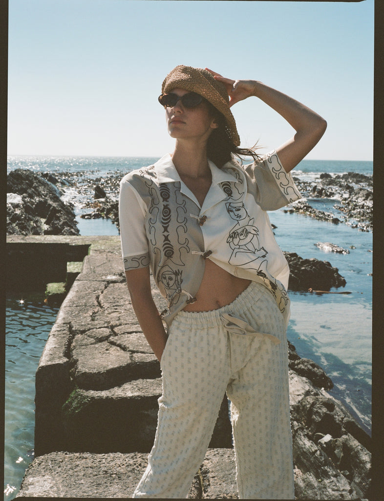 woman puts hand on hat while looking into distance