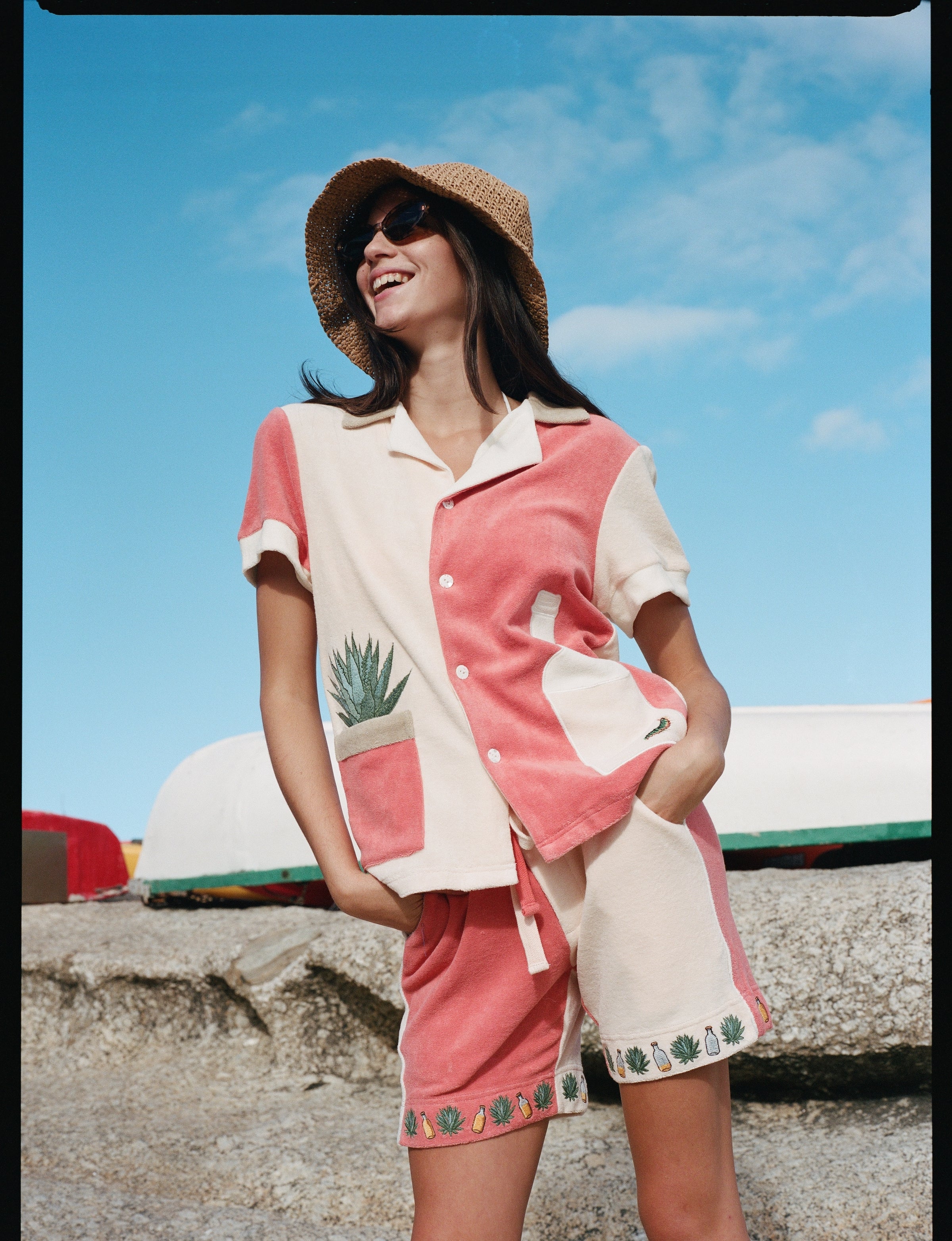 Female model standing wearing the full terry cloth Gusanito set along with a woven sun hat and sunglasses