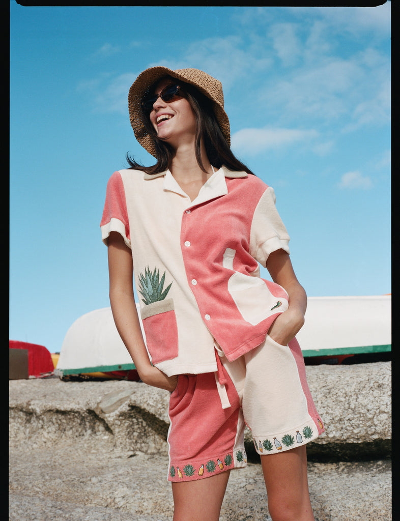 Female model standing wearing the full terry cloth Gusanito set along with a woven sun hat and sunglasses