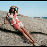 Female model leaning on a rock wearing the full terry cloth Gusanito set along with a woven sun hat