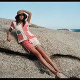 Female model leaning on a rock wearing the full terry cloth Gusanito set along with a woven sun hat