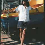 male model relaxing against a boat in his fruits de mer swim trunks