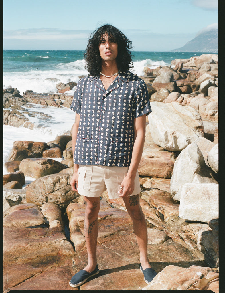 Male model wearing shirt with stowaway shorts on beach
