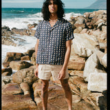 man stands amidst rocks by the ocean