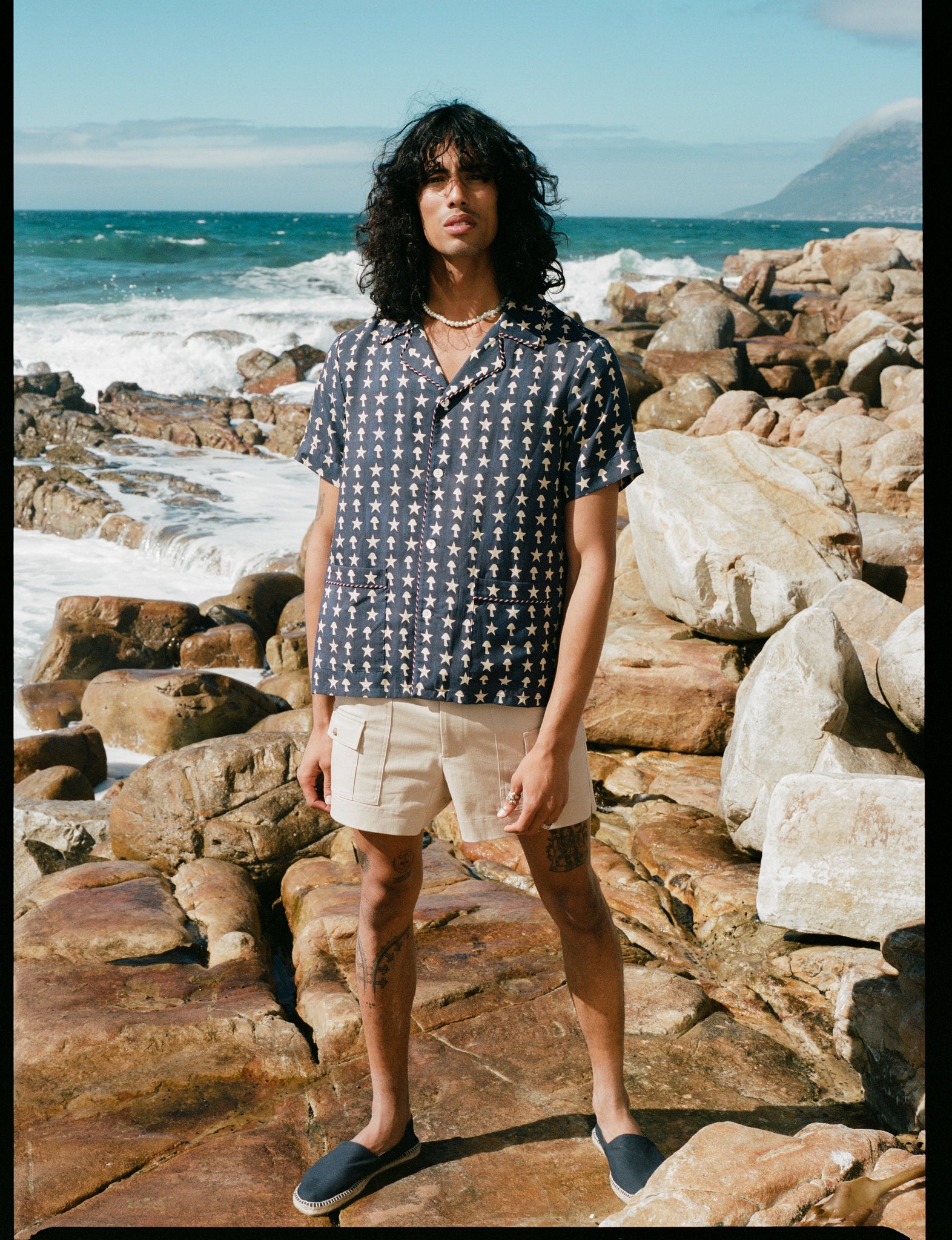 man stands amidst rocks by the ocean