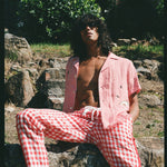 man with unbuttoned shirt sits on rock