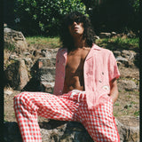 man with unbuttoned shirt sits on rock