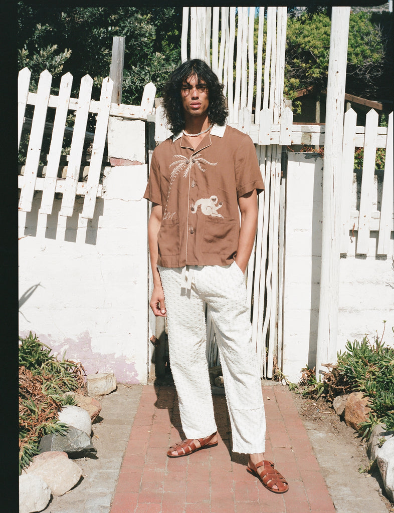 male model posing in the shirt with white pants and brown sandals