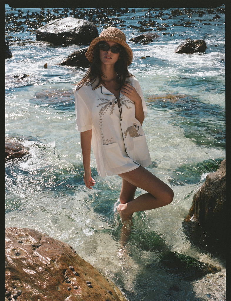 female model wearing shirt in the water with one leg up