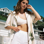 woman looks at camera with unbuttoned 'Cabannabis' shirt