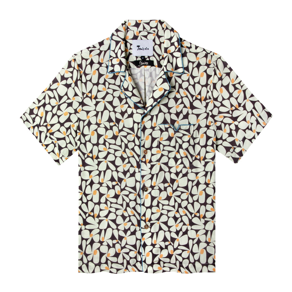 Front view of the sunny disposition hawaiian tee, with a pattern of an abstract field of daisies as well as four brown buttons down the front and blue piping on the collar and front pocket 