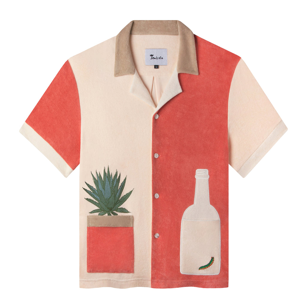 Tombolo salmon and light pink cotton terry cloth shirt with a light pink tequila bottle with a green worm inside on the right and an agave plant in a salmon colored pot on the left side, has a beige collar and four white buttons