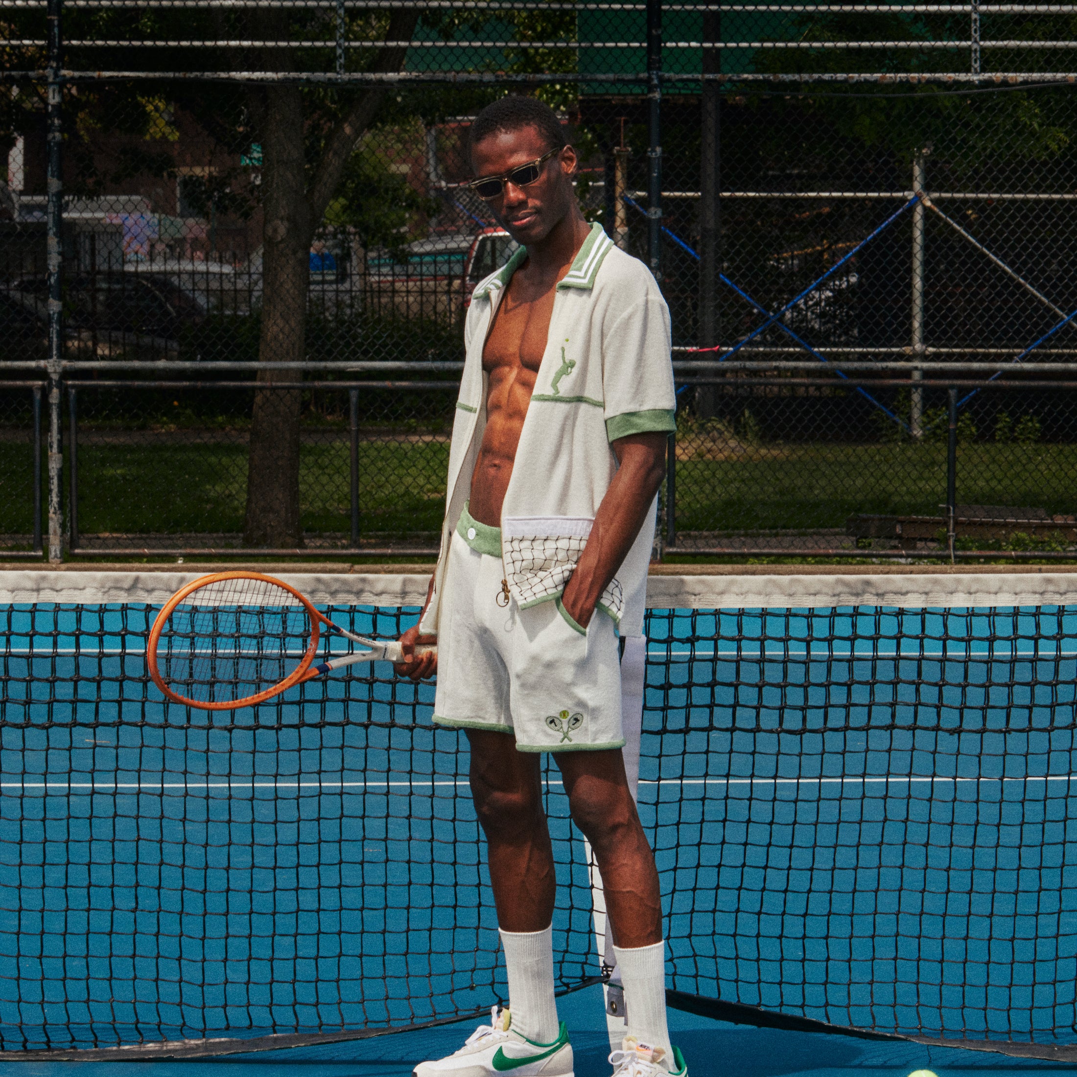 male model in full fault one set on tennis court with shirt unbuttoned