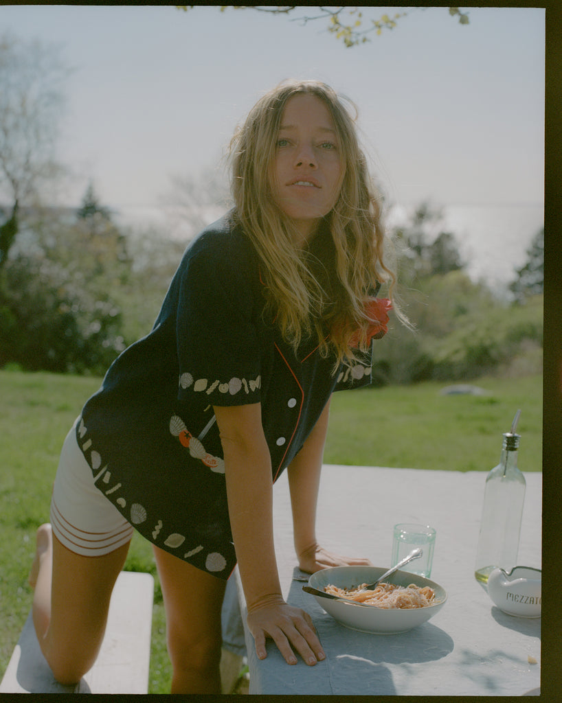 Female model leaning over a bowl of spaghetti wearing the vongole crop