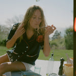 Female model wearing the shirt while eating spaghetti outdoors
