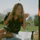 Female model wearing the shirt while eating spaghetti outdoors