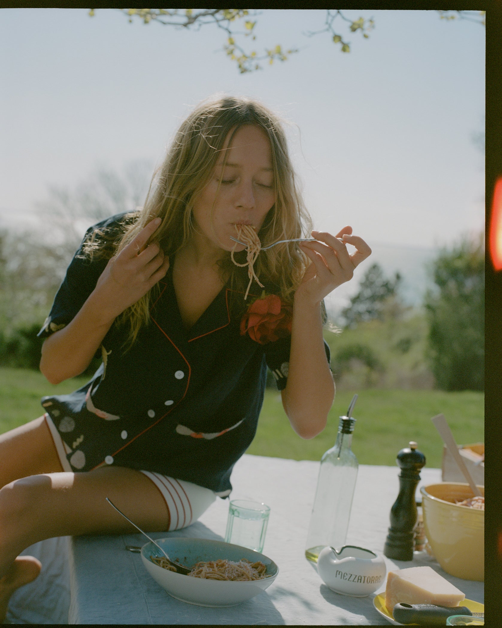 Female model wearing the shirt while eating spaghetti outdoors