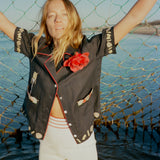 Female model wearing vongole crop holding up a fishing net in the ocean