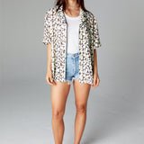 Shirt unbuttoned over a white tank top and jean shorts on a female model