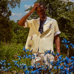 Man stands looking down at blue flowers
