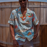 Male model wearing the top and khaki stowaway shorts leaning on fence 
