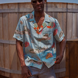 Male model wearing the top and khaki stowaway shorts leaning on fence 