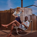 Female model standing in the shirt and male model lounging on a chair in the shirt