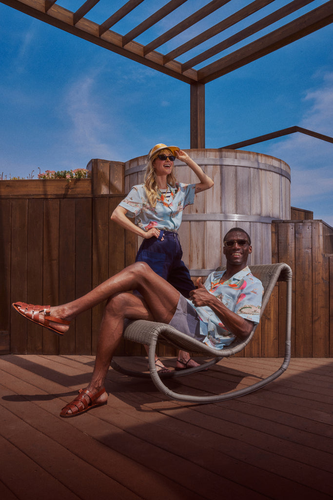 Female model standing in the shirt and male model lounging on a chair in the shirt