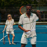 Male and female models both in full fault one set holding rackets and balls. male model has hand in left cabana pocket