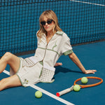 Female model sitting on tennis court in full fault one set