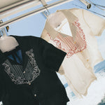 Cloud Grey Fruits de Mer shirt next to the Black fruits de mer shirt