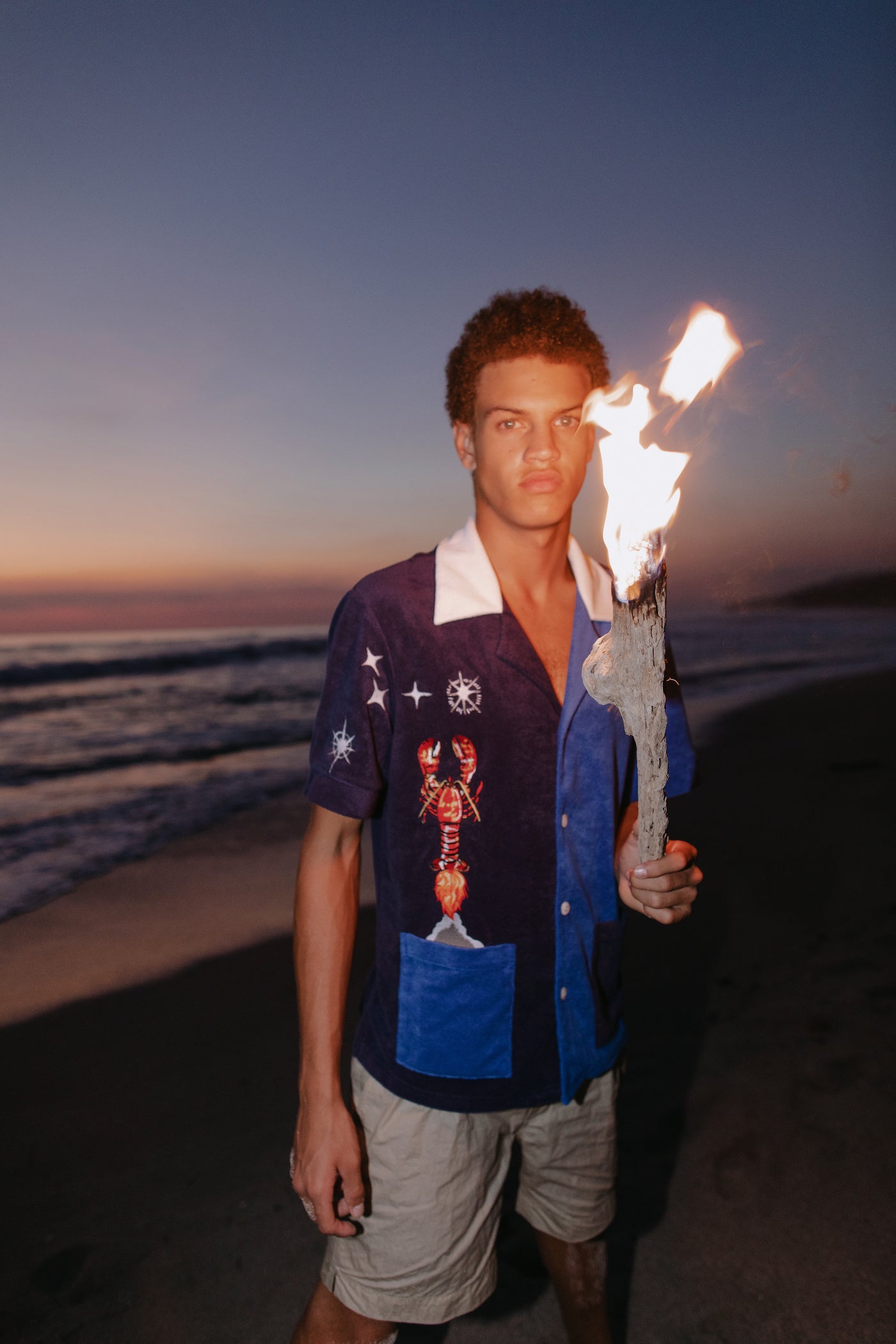 Male model wearing shirt holding a burning stick on the beach