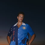 Male model looking down at camera at sunset wearing top