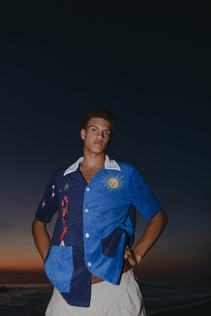 Male model looking down at camera at sunset wearing top