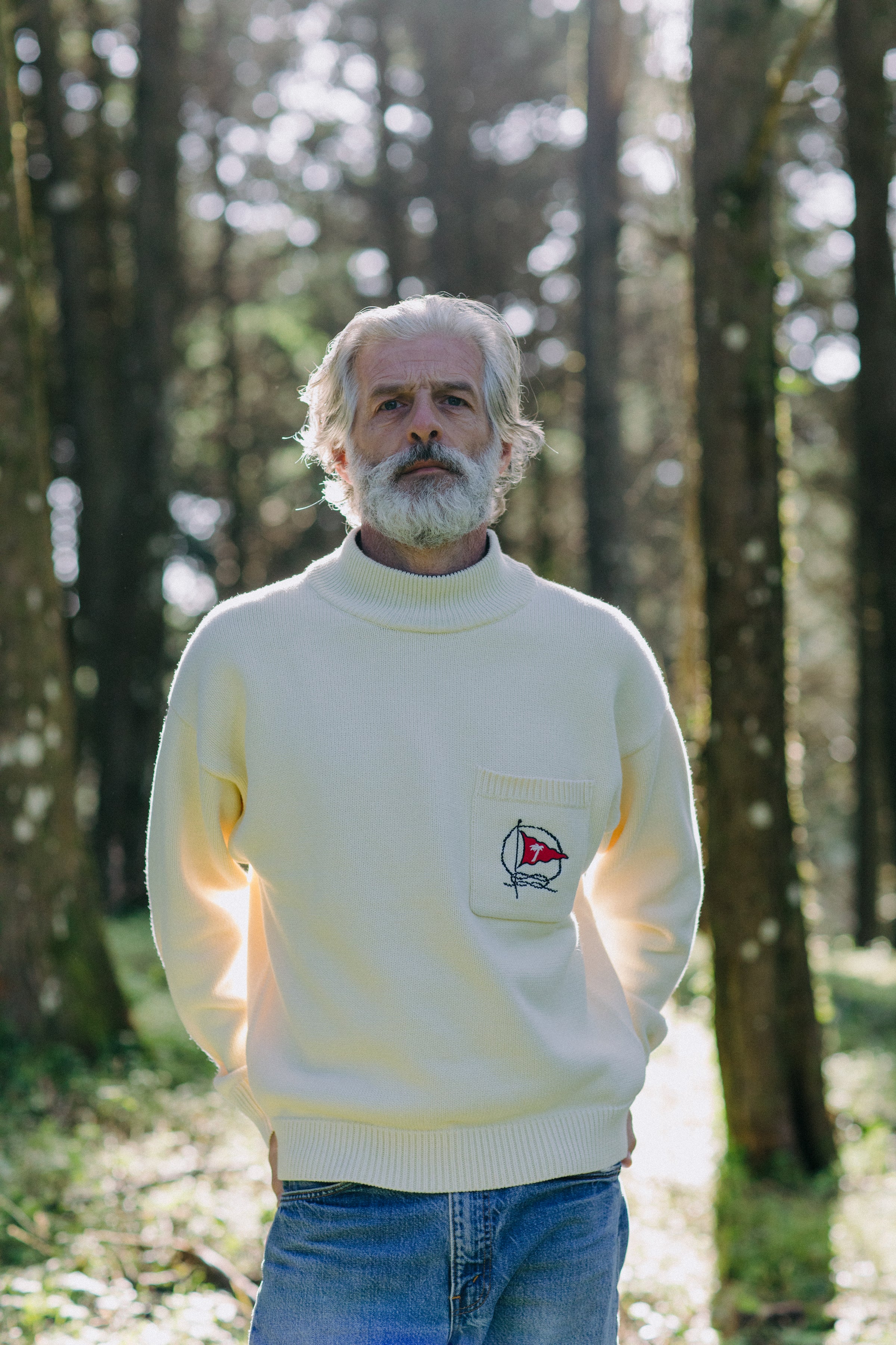 Man stands in forest looking straight at camera