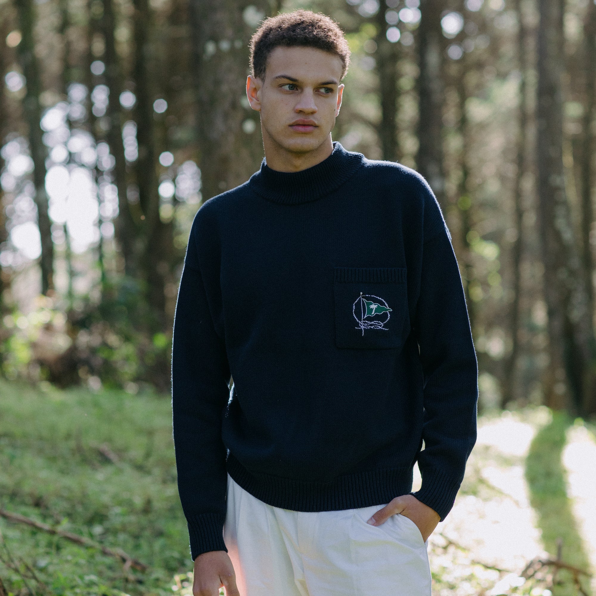 Man stands in forest looking off camera