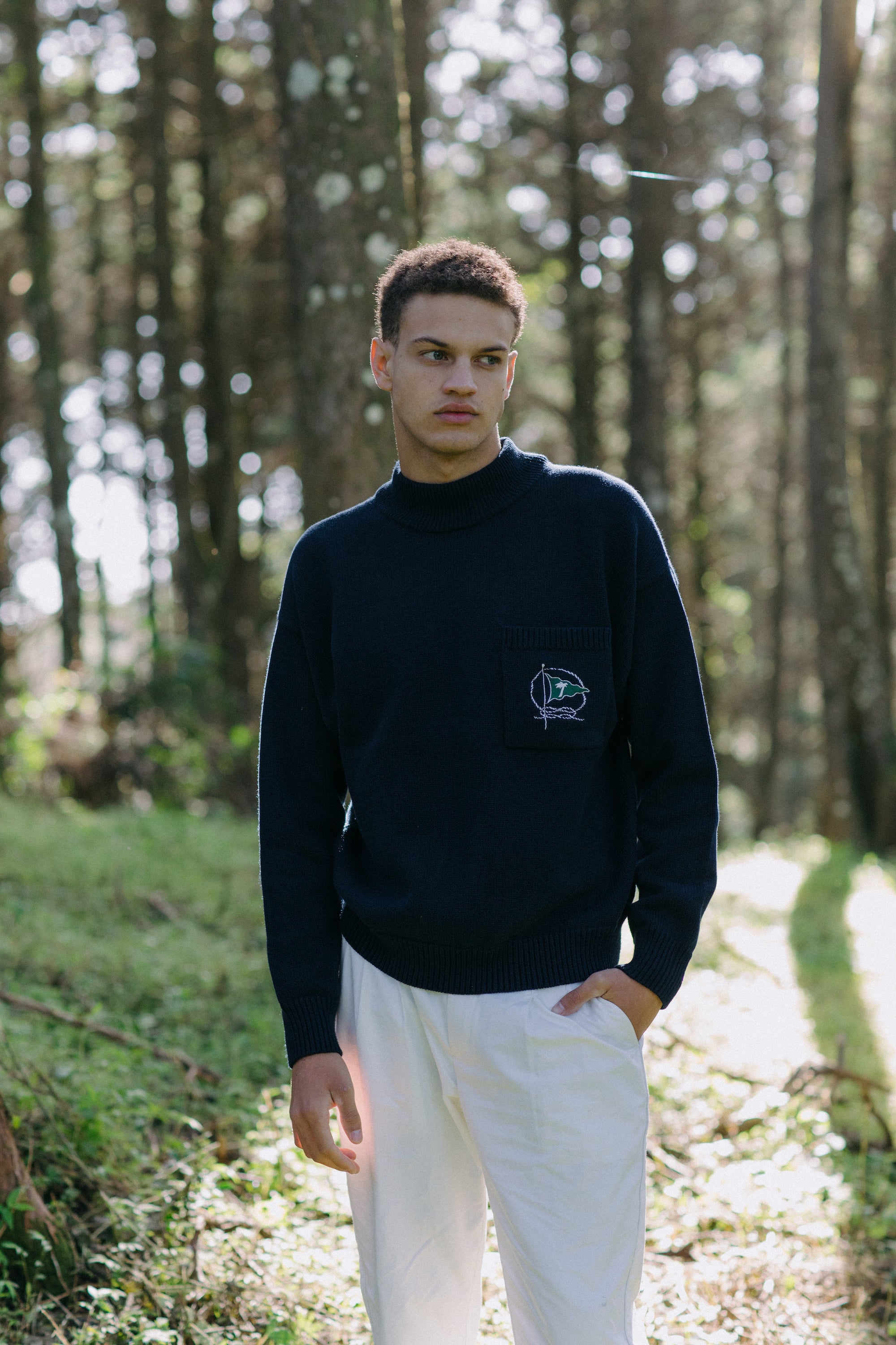 Man stands in forest looking off camera