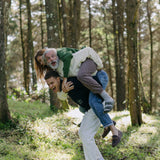 younger man carries older man and woman on his back, laughing as they all display different colors of the sweater
