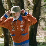 older male model posing in forest in the organic cotton terry cloth long sleeve polo cabana shirt for your new softest sweater that is smart and fun with embroidered mushrooms 