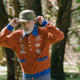 older male model posing in forest in the organic cotton terry cloth long sleeve polo cabana shirt for your new softest sweater that is smart and fun with embroidered mushrooms 