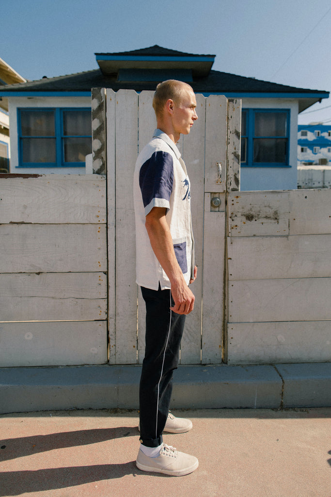 Side view of pants on male model, showing white stripe down side