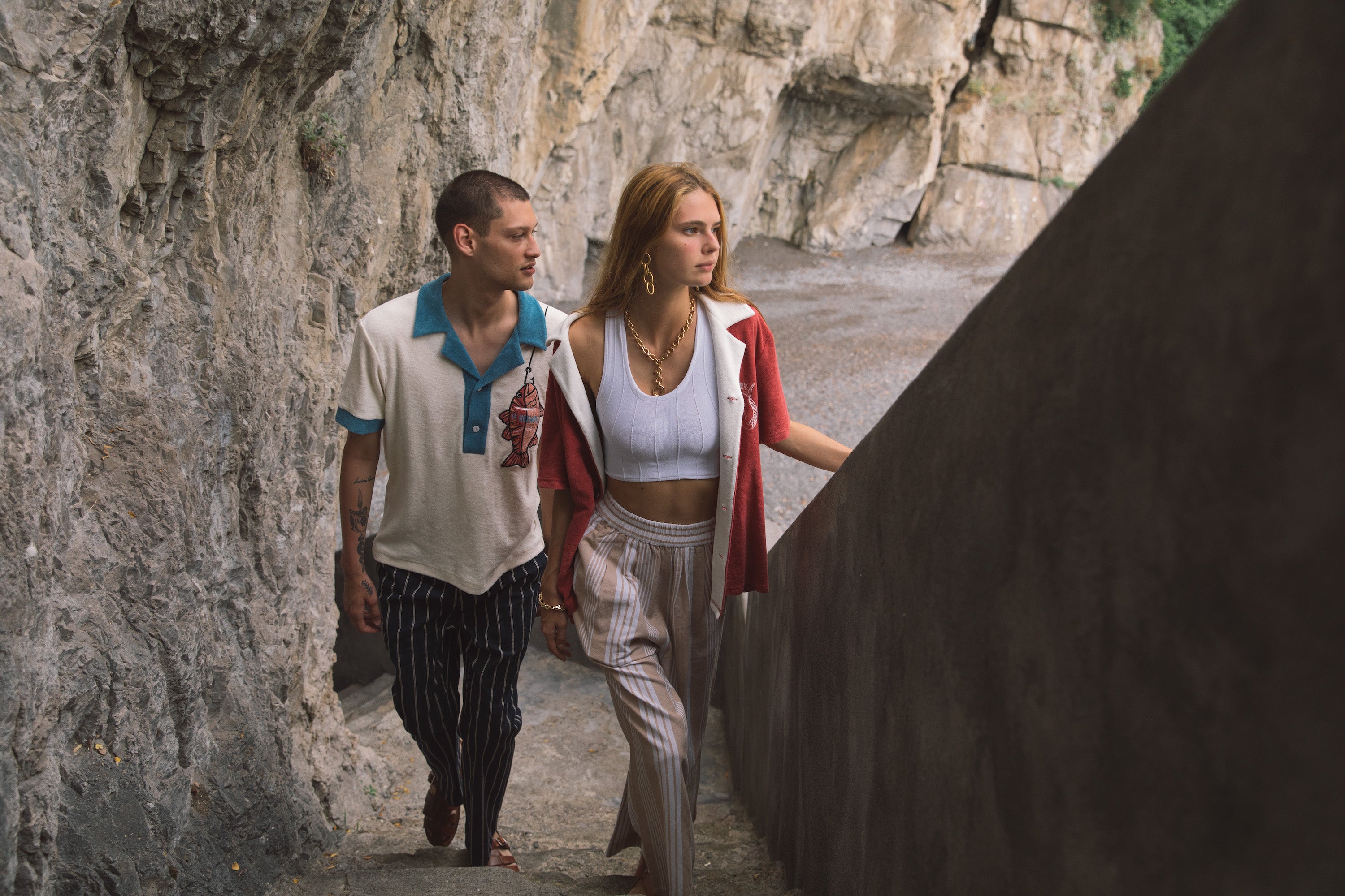 Male model wearing pop over next to female model walking up stairs