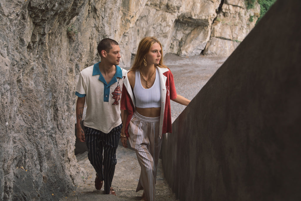 Male model wearing pop over next to female model walking up stairs