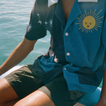 Male model wearing shirt with black shorts on side of a boat