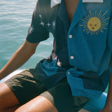 Male model wearing shirt with black shorts on side of a boat
