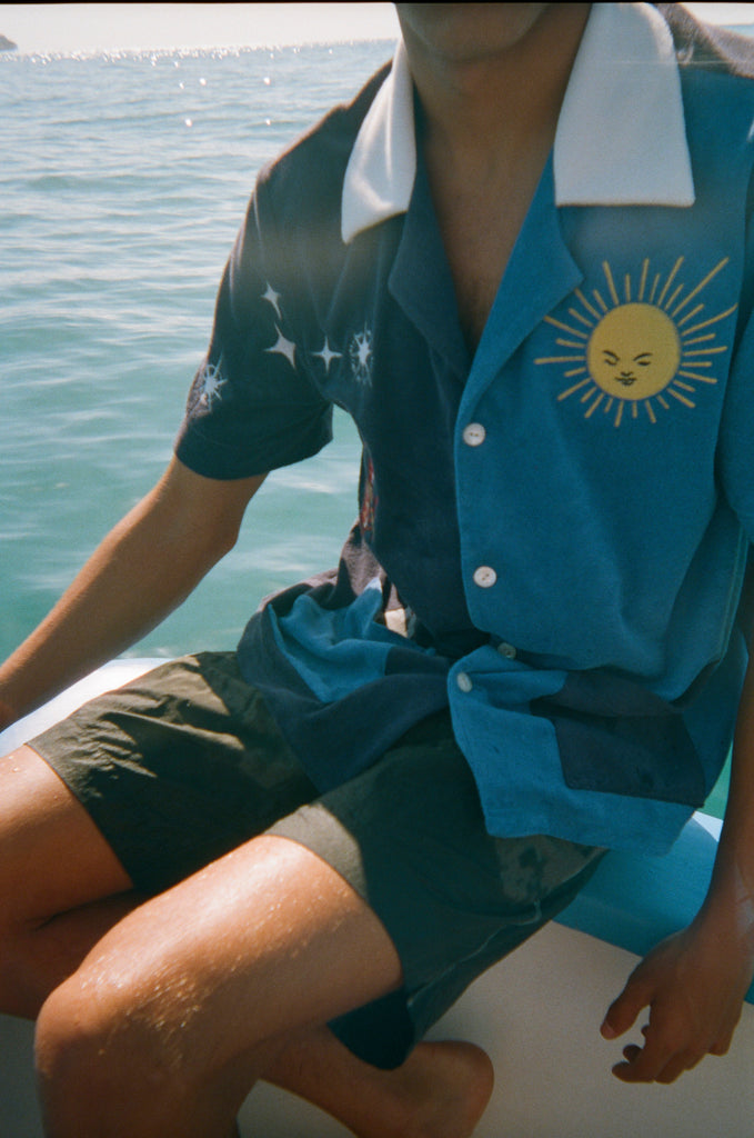 Male model wearing shirt with black shorts on side of a boat