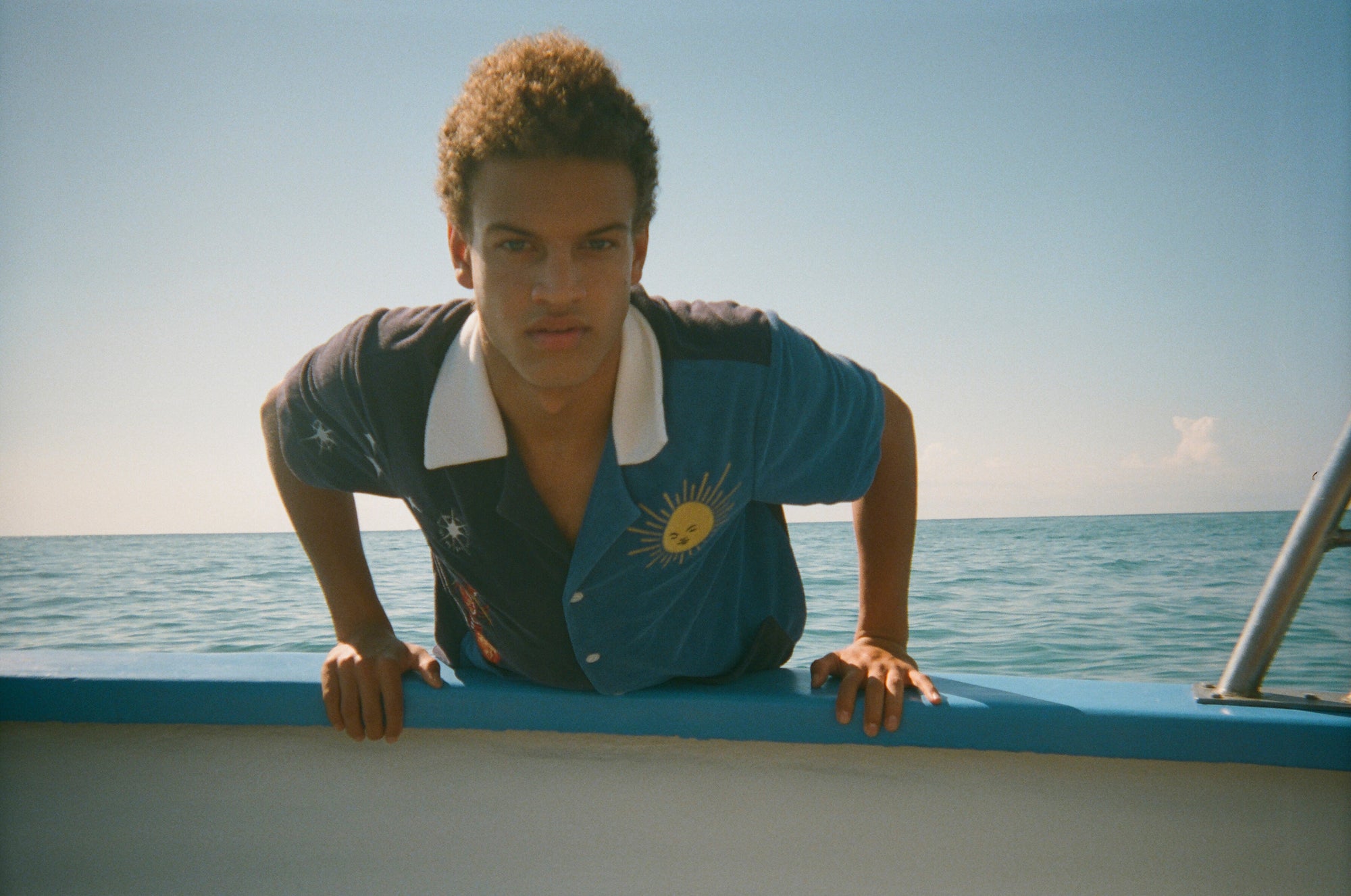 Male model leaning over side of boat wearing shirt