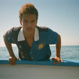 Male model leaning over side of boat wearing shirt